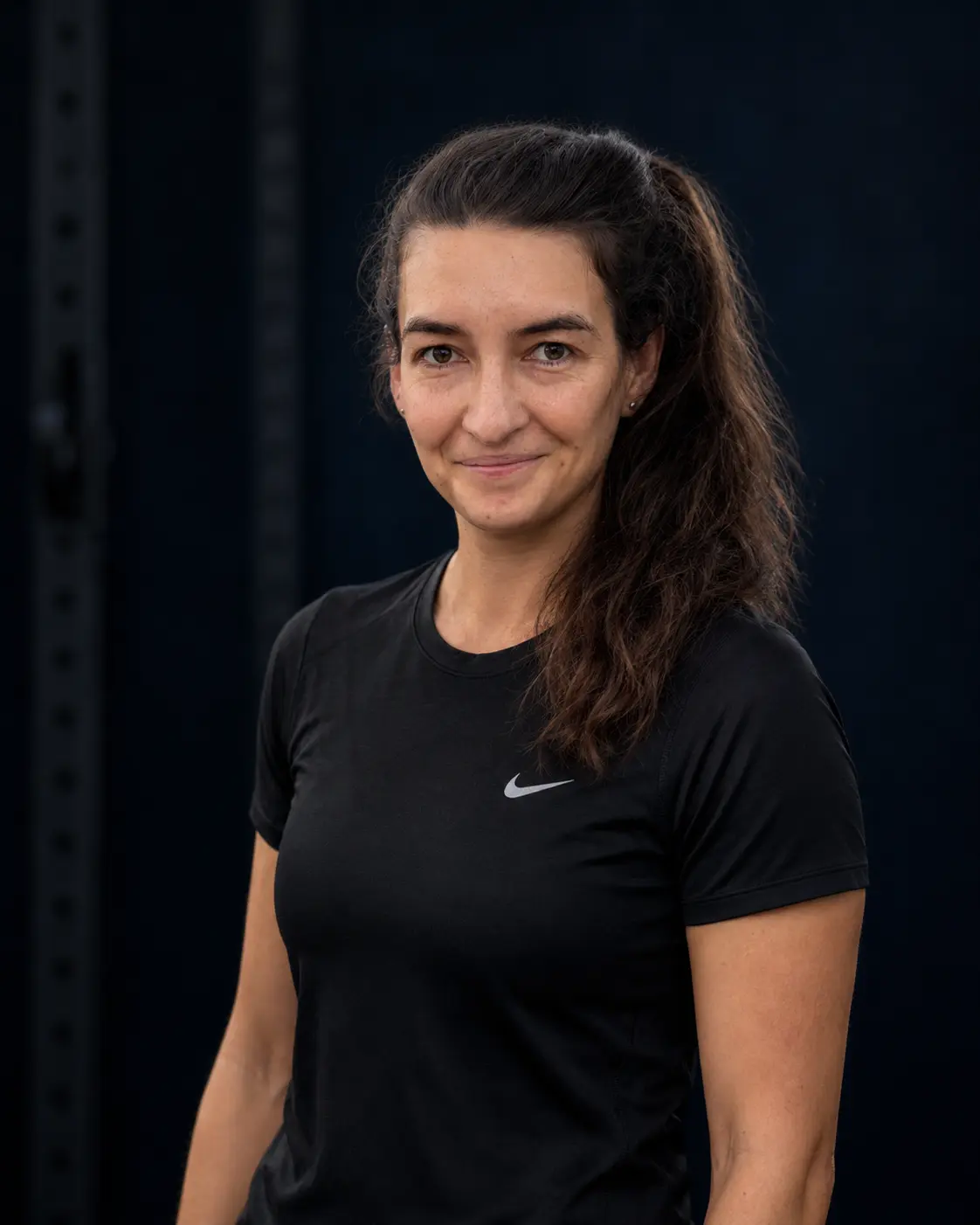 Karolina, trenerka NCKF Kraków, w sportowej koszulce na tle nowoczesnej przestrzeni treningowej.