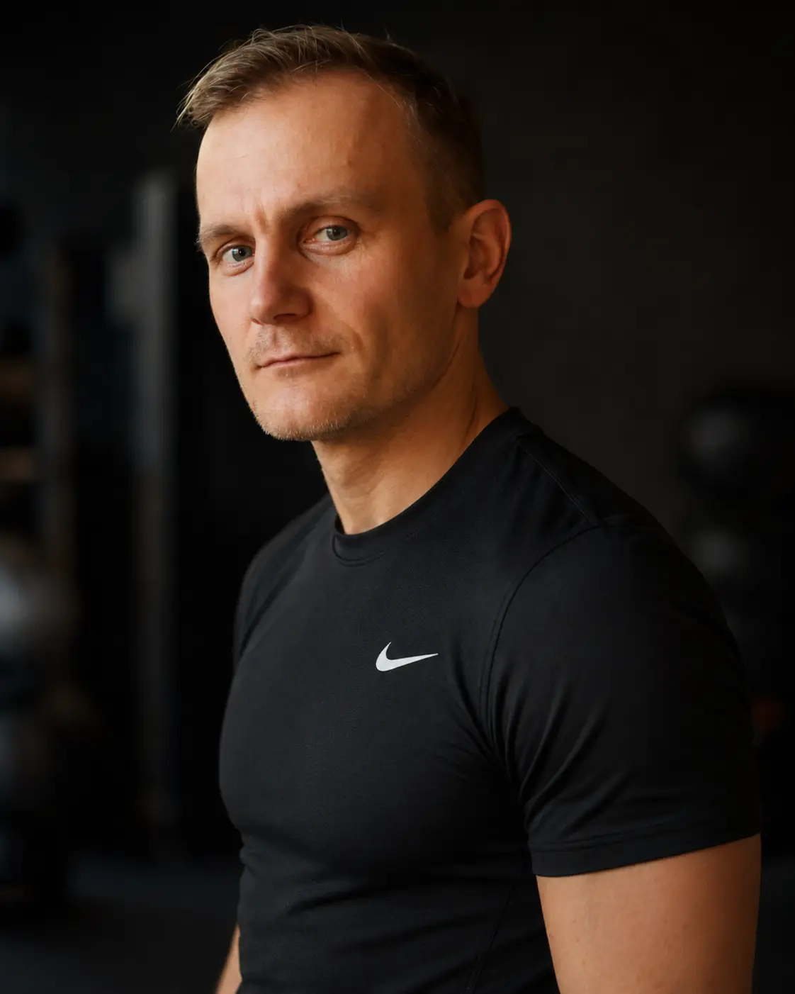 Sławek, trener NCKF Kraków, w czarnej koszulce Nike na tle sali treningowej